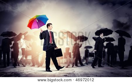 Obraz ładny biznesmen z parasolem, chodzenie w tłumie ludzi