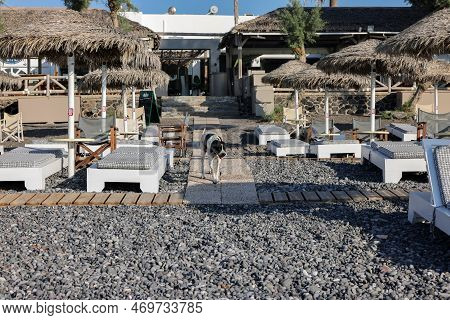 Kamari, Santorini, Greece - July 3, 2021: Sun Loungers On The Black Volcanic Beach Of Kamari In Sant