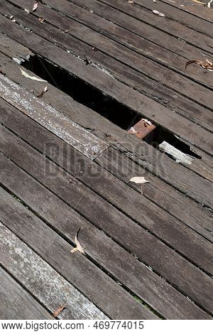Dangerous, Rotted, Unvarnished, Wooden Decking Floorboards With Holes, Gaps And Dry Leaves, In An Ou