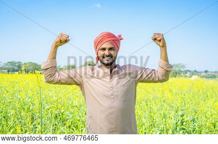 Happy Famer Showing Stroing Gesture Using Two Hands At Farmland By Looking At Camera - Conept Of Con