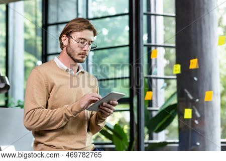 Young Successful Thinking Programmer Inside Loft Style Office Uses Tablet Computer, Young Blond Man 