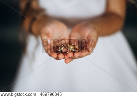 A Child Holds Gold Rings At A Wedding