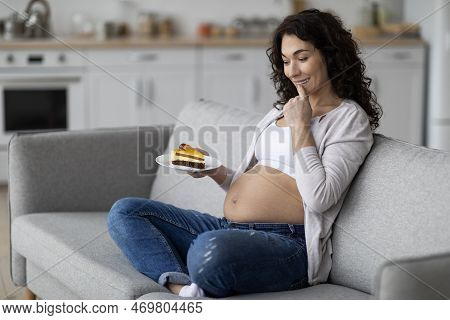 Pregnancy Crawings. Excited Pregnant Woman Holding Piece Of Cake At Home