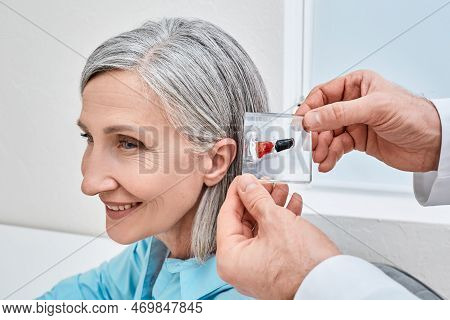 Invisible In-the-canal Hearing Aids. Doctor Demonstrates Display Stand With Itc And Ite Hearing Aids