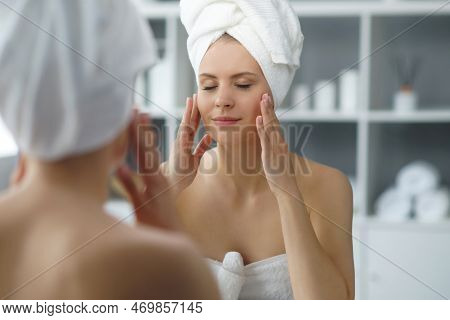 Young Woman Sits In The Bathroom In Front Of The Makeup Mirror And Does Cosmetic Procedures. Beautif