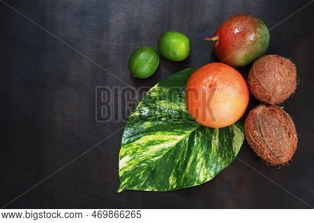 Top View Of Juicy Tropical Fruits On Dark Wooden Background, Flat Lay. Greyfruit, Mango, Coconuts An