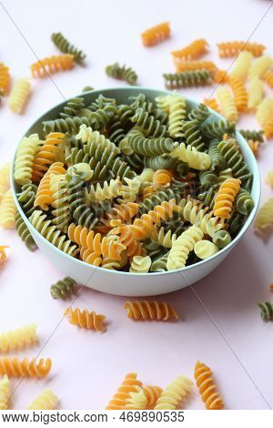 Organic Fusilli Tricolore Spilling On Pink Background
