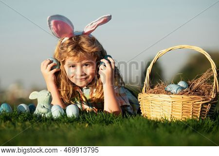 Child Boy With Easter Eggs In Basket Outdoor. Kid Laying On Grass In Park On Sky Background With Cop