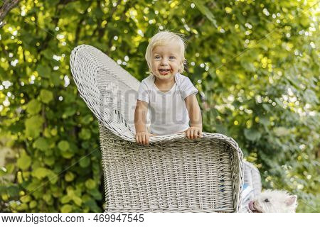 A Clumsy Baby Smeared With Chocolate. The Baby Is Enjoying Childhood, A Blue-eyed Child In A White B
