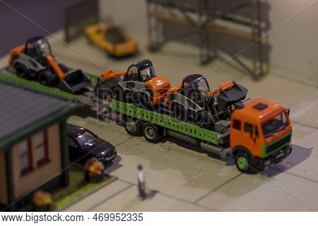 A Cargo Toy Car Carries Forklifts In The Back, There Is A House, An Urban Landscape.