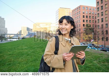 Happy Young Brunette Girl, Asian Woman Walks Around City With Tablet, Goes To University With Her Di