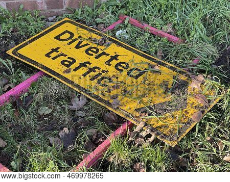 Cropped Shot Of Diverted Traffic Sign Thrown Away In The Grass Covered In Mud