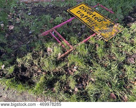 Yellow Diverted Traffic Sign Thrown Away In The Grass Near Car Road, Copy Space