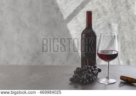 Red Wine Bottle, Wine Glass And Grape On Grey Concrete Background. Wine Making And Wine Degustation 