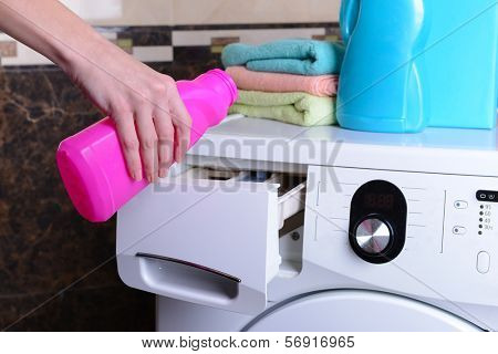 Female hands poured powder in washing machine close-up