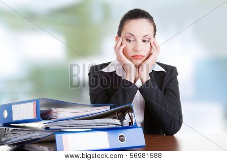 Sad woman with ringbinders sitting at the desk. Tired and exhousted business woman. 