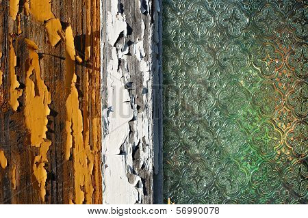 An old wooden house window with pealing off paint and old decorated window glass