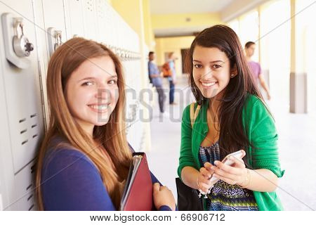 High School Students By Lockers Looking At Mobile Phone