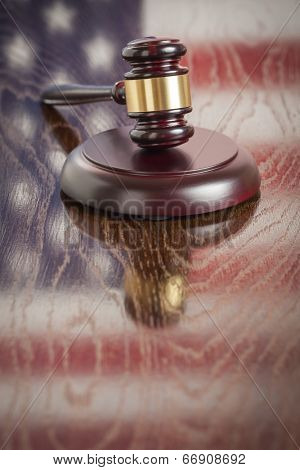 Wooden Gavel Resting on American Flag Reflecting Table.