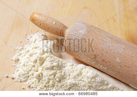 detail of wooden cutting board with flour and rollingpin