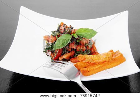 vegetable salad : cherry tomatoes and basil with sweet baked potato served on white plate with sauceboat full blask soy sauce on wood