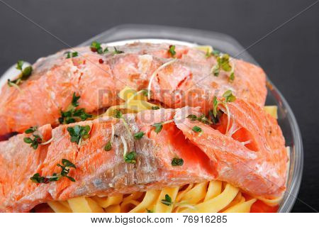 fresh fried natural pink salmon on italian traditional tagliatelle backed with tomato and vegetables served over black wooden table