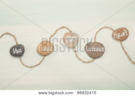 Five stones with german text for: courage, happiness, luck, trust and power. Concept for balance and well-being.
