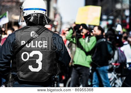 Detail Of The Back Of A Police Facing Protesters.
