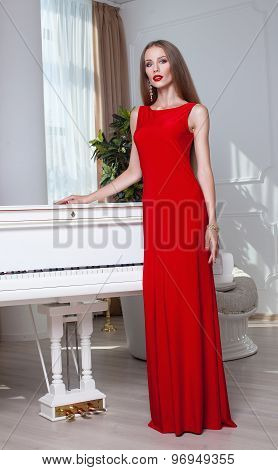 Beautiful brunette woman in a red dress. Studio shot. Long hair. Red lips.