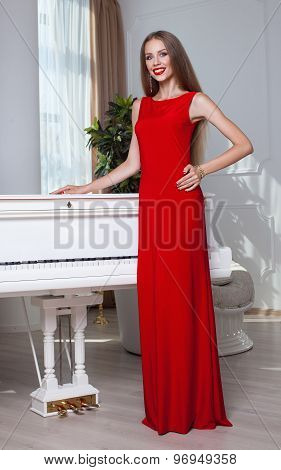Beautiful brunette woman in a red dress. Studio shot. Long hair. Red lips.