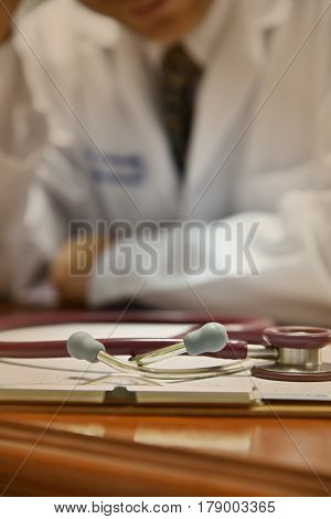 Closeup The Stethoscope On Desk In  Clinical Room; Background Is Doctor Blur.