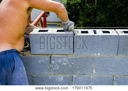 construction worker bricklayer installing red brick with trowel putty knife outdoors