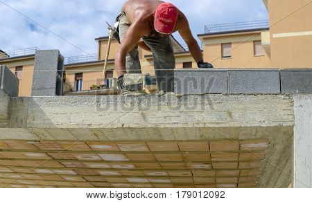 construction worker bricklayer installing red brick with trowel putty knife outdoors