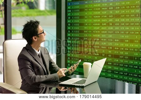 Smart businessman look at head-up display stock market board. He uses it for decision to order stock on his smartphone. Head-up Display Concept