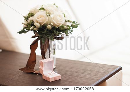 Wedding bouquet of yellow and white roses and blue fresia lying on wooden floor.