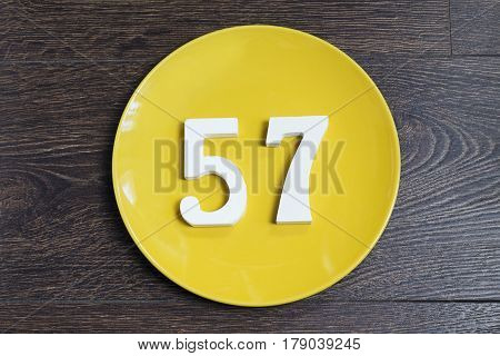 The number fifty-seven on the yellow plate and brown background.