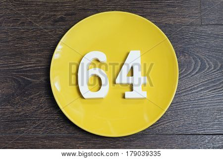 The number sixty-four on a plate yellow and brown background.
