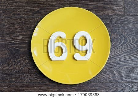 The number sixty-nine on the yellow plate and brown background.