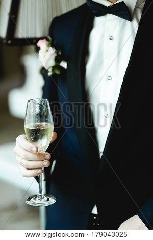 Man In Tuxedo With Boutonniere Holds A Champagne Flute