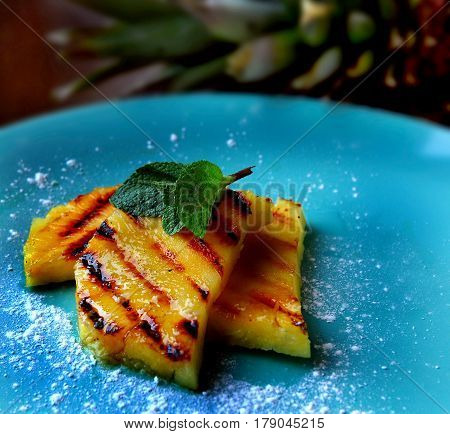 Photo of beautiful and useful dinner. Pineapple cooked on the grill and decorated with mint.