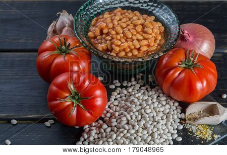 Traditional English food - baked white beans in tomato sauce and ingredients ready to cook - tomatoes dried white beans and onion