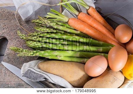 Ingredienrs for seasonal spring tasty vegetarian dinner - fresh green asparagus carrot potato and chicken eggs ready to cook.