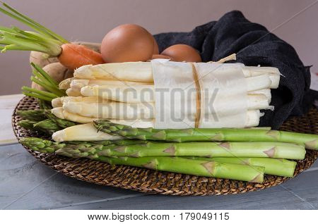 Ingredienrs for seasonal spring tasty vegetarian dinner - fresh white and green asparagus carrot potato and chicken eggs ready to cook.