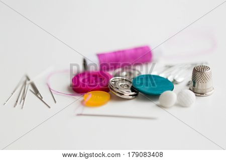 needlework and tailoring concept - sewing buttons, needles, pins and thread spool