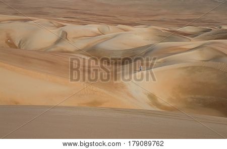 young man walking in sand dunes in Liwa desert in Abu Dhabi
