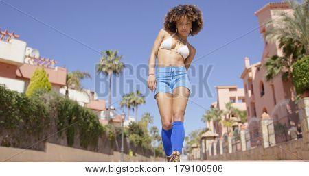 Female wearing blue shorts and knee-high socks looking at camera on city background. 