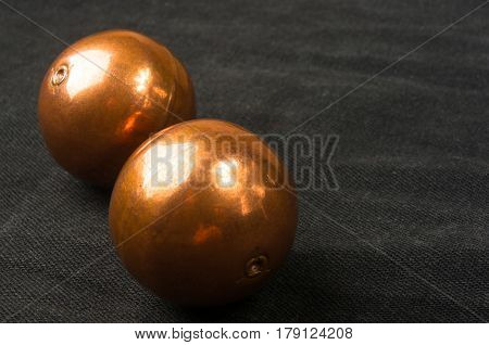 pair of copper Chinese singing balls Baoding of health for hands on black background