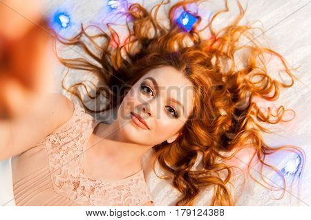 Sexy lazy girl lying on the bed taking self photo. Woman relaxing lazing in the bedroom.