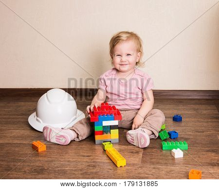 Funny baby toddler building a house of plastic constructor blocks. Happy child playing with constructor toys.