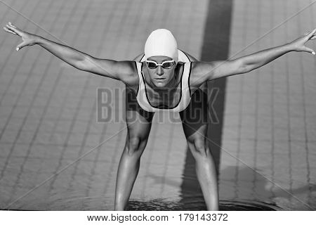 Female swimmer streching on poolside, black and white